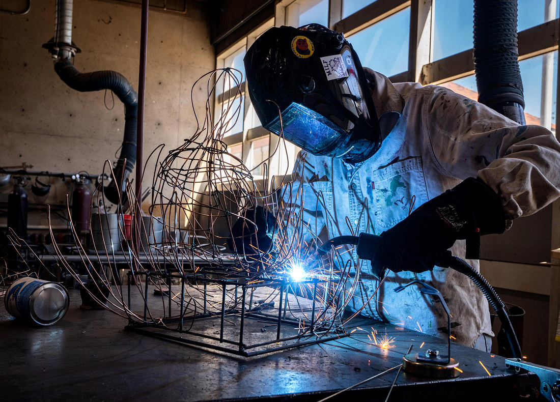 A student works on a sculpture project in a metalworking studio.