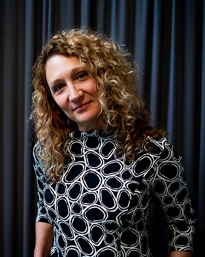 Carrie Hanson, standing in front of a blue curtain