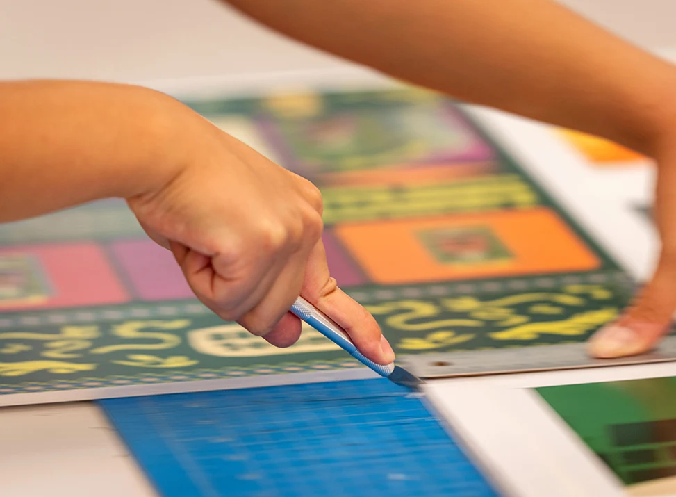 A student uses a craft knife to trim out a poster design