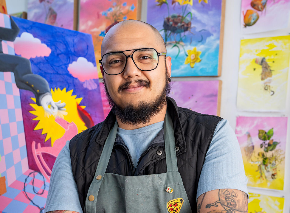 Student stands in front of a wall of his paintings