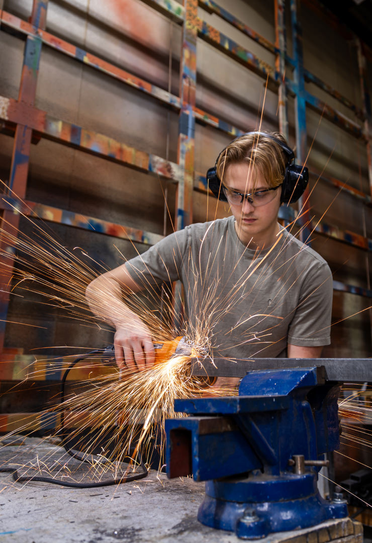 theatre tech student using a metal cutter