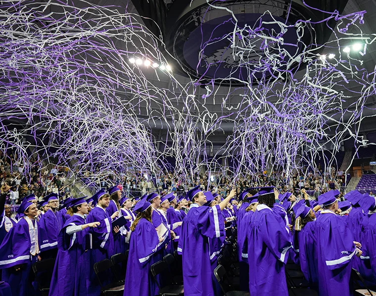 TCU graduates in commencement regalia pop confetti and streamers overhead