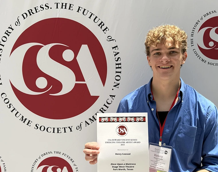 Henry Cawood hold award certificate in front of Costume Society of America backdrop